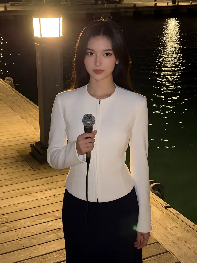 原创夜航音频图：成年女航线员穿白色外套站在夜间码头灯下，手里拿着麦克风
